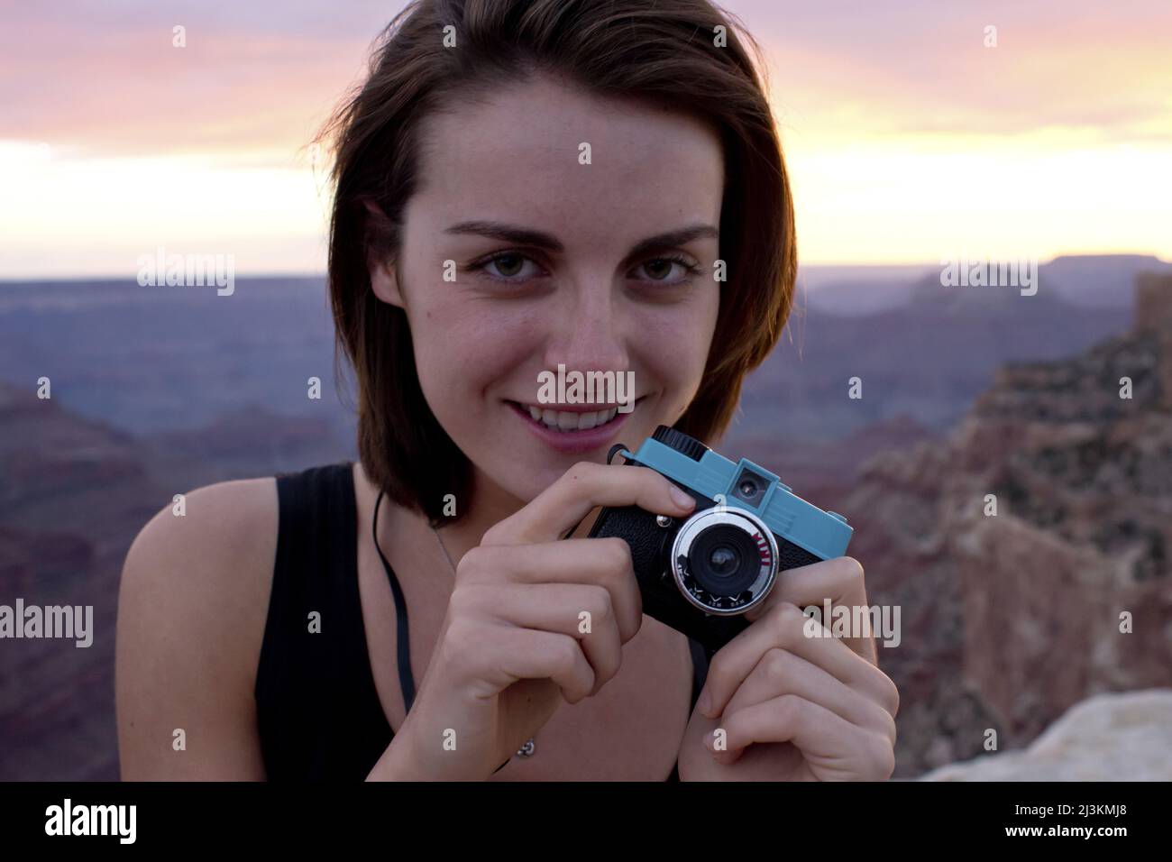 Eine junge Frau fotografiert den Grand Canyon bei Sonnenuntergang. Stockfoto