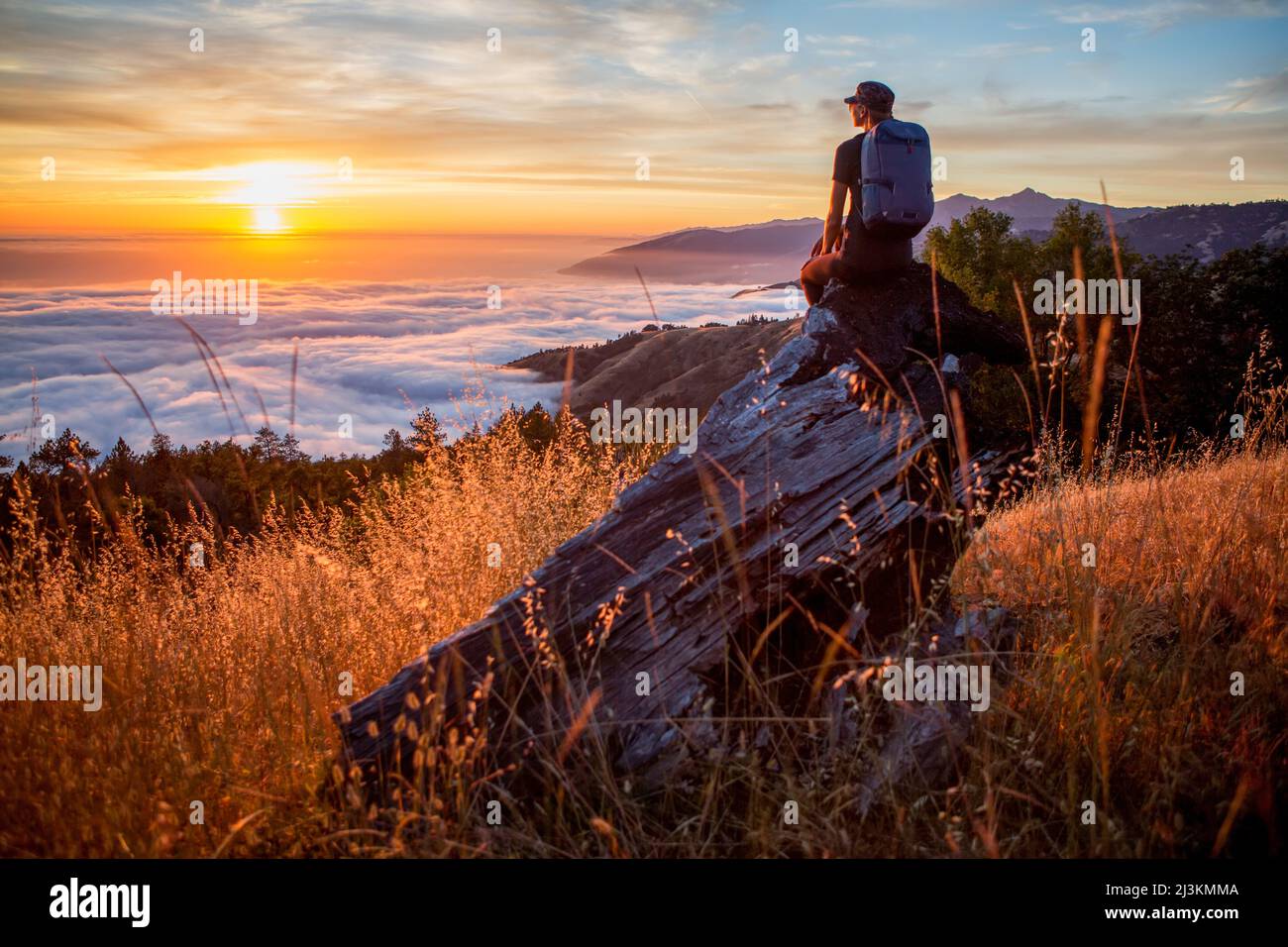 Eine junge Frau, Blick auf den Sonnenuntergang über den Wolken in Big Sur, Kalifornien, USA. Stockfoto