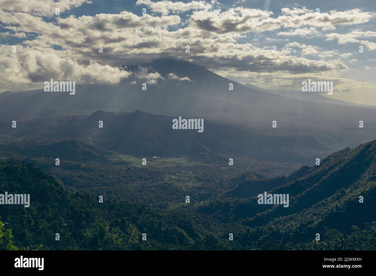 Sonnenlicht, das durch Wolken in ein Tal und eine bergige Landschaft unter uns strömt, von Lahangan Sweet aus gesehen; Kabupaten Karangasem, Bali, Indonesien Stockfoto