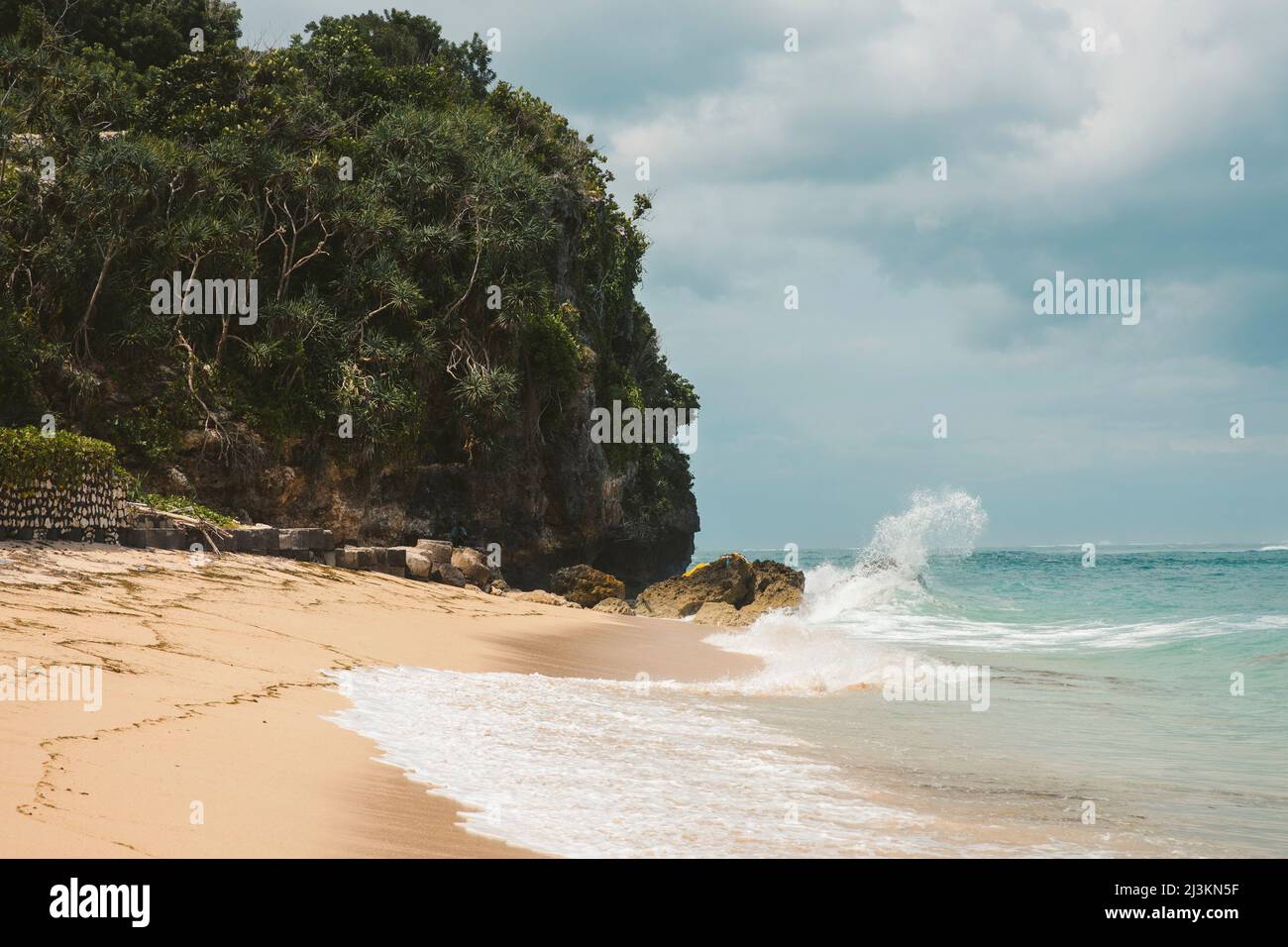 Wellen schlagen gegen die Felsen, und die Brandung rollt auf den Sand am Geger Beach im Nusa Dua Resort Gebiet; Geger Beach, Badung, Bali, Indonesien Stockfoto