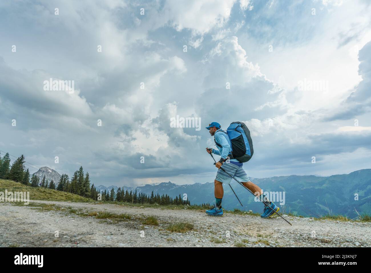 Ein Athlet in den Redbull X Alps, ein Gleitschirmrennen, wandert mit Entschlossenheit entlang des Bergweges zu einem Gipfel, um seinen Gleitschirm unter ... Stockfoto