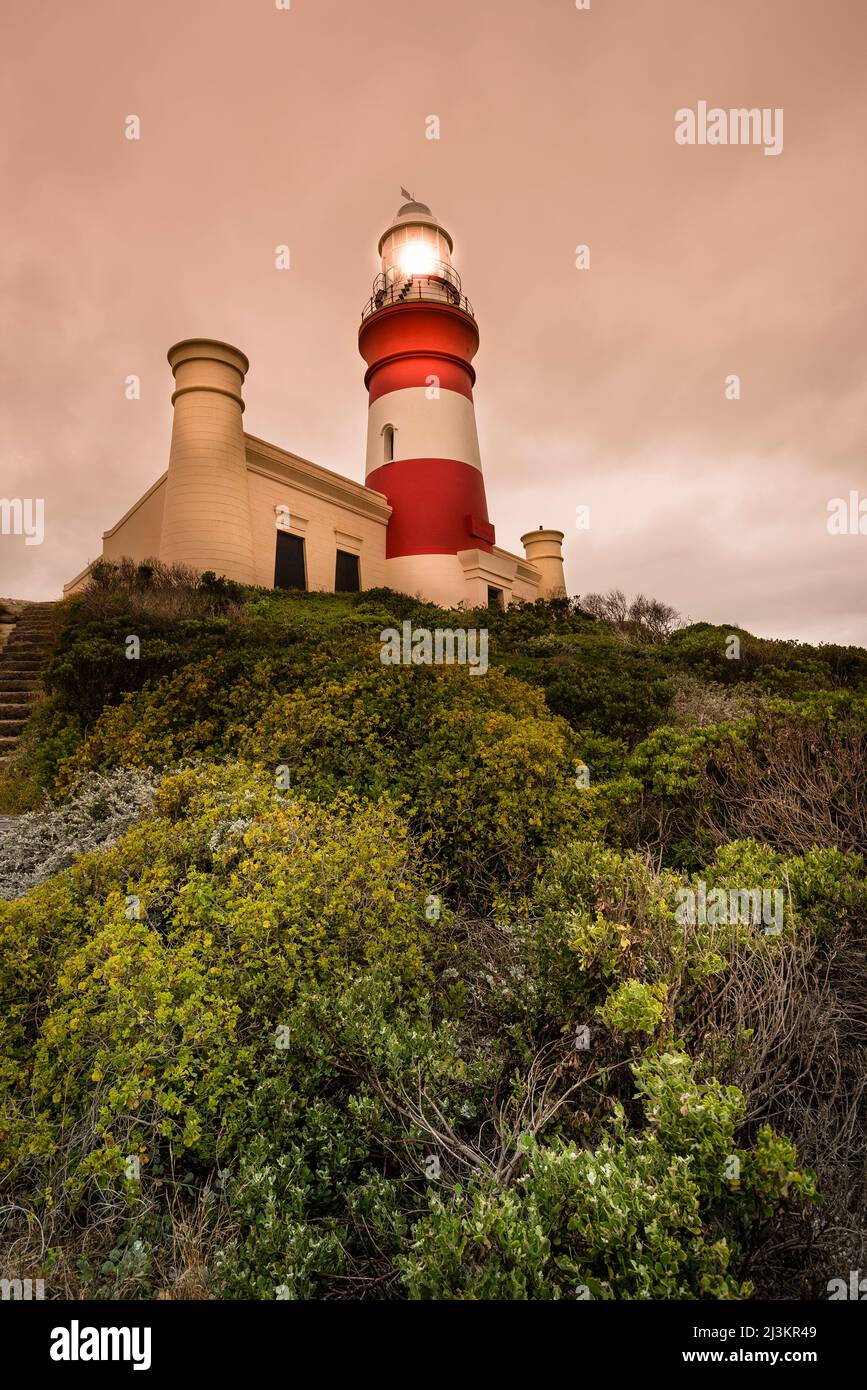 Leuchtturm Cape Agulhas, beleuchtet in der Abenddämmerung, Agulhas National Park; Cape Agulhas, Western Cape, Südafrika Stockfoto