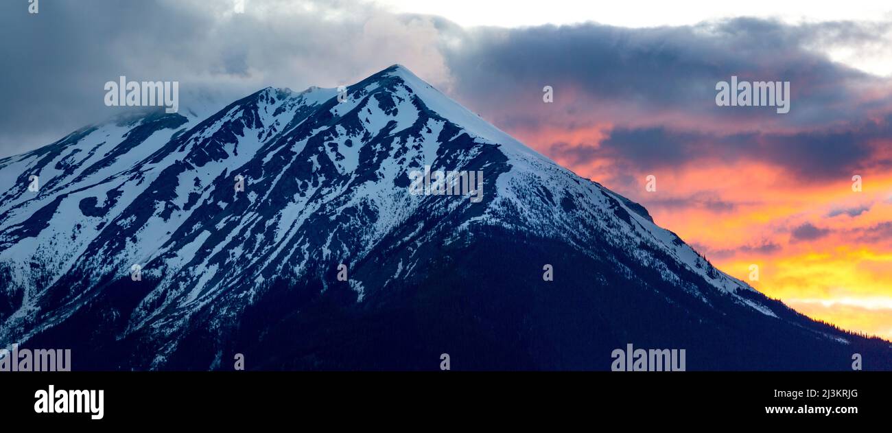 Der zerklüftete Gipfel des Hudson Bay Mountain ist mit Schnee und bunten, glühenden Wolken bedeckt; Smithers, British Columbia, Kanada Stockfoto