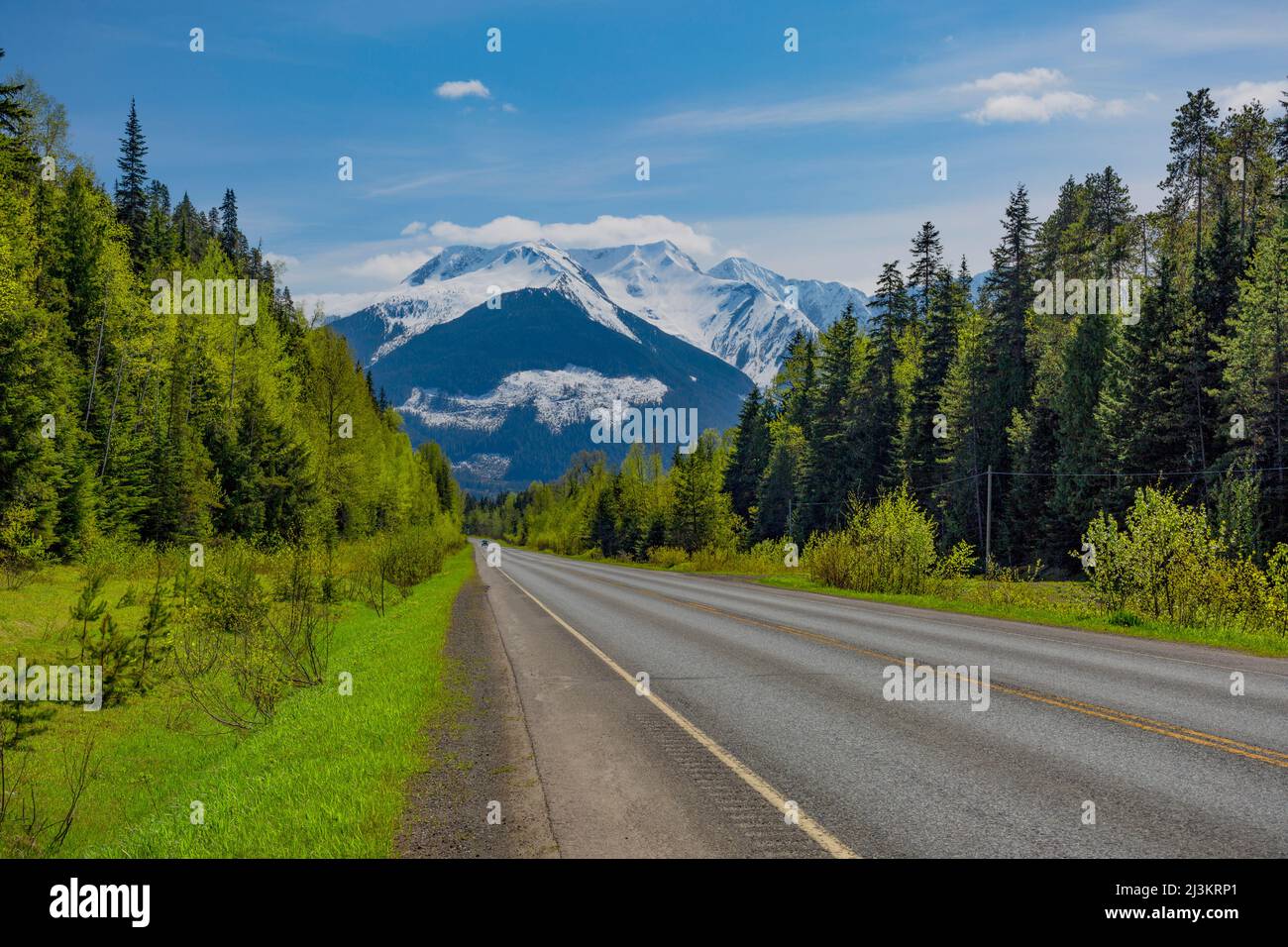 Autobahn durch Wälder zu einer majestätischen Bergkette; British Columbia, Kanada Stockfoto