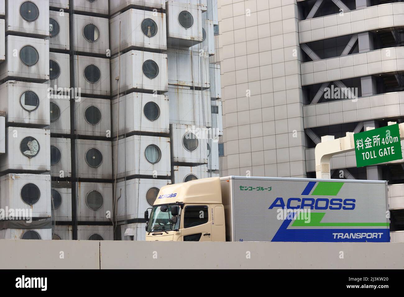 TOKIO, JAPAN - 13. Januar 2022: Ein Lastwagen auf dem Shuto Expressway, Tokyos städtischer Autobahn, fährt unter einer Mautstelle durch den Nakagin Capsule Tower Stockfoto