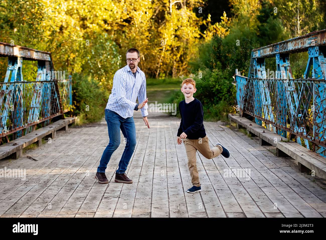 Vater und Sohn tanzen im Herbst auf einer Brücke in einem Park; Edmonton, Alberta, Kanada Stockfoto