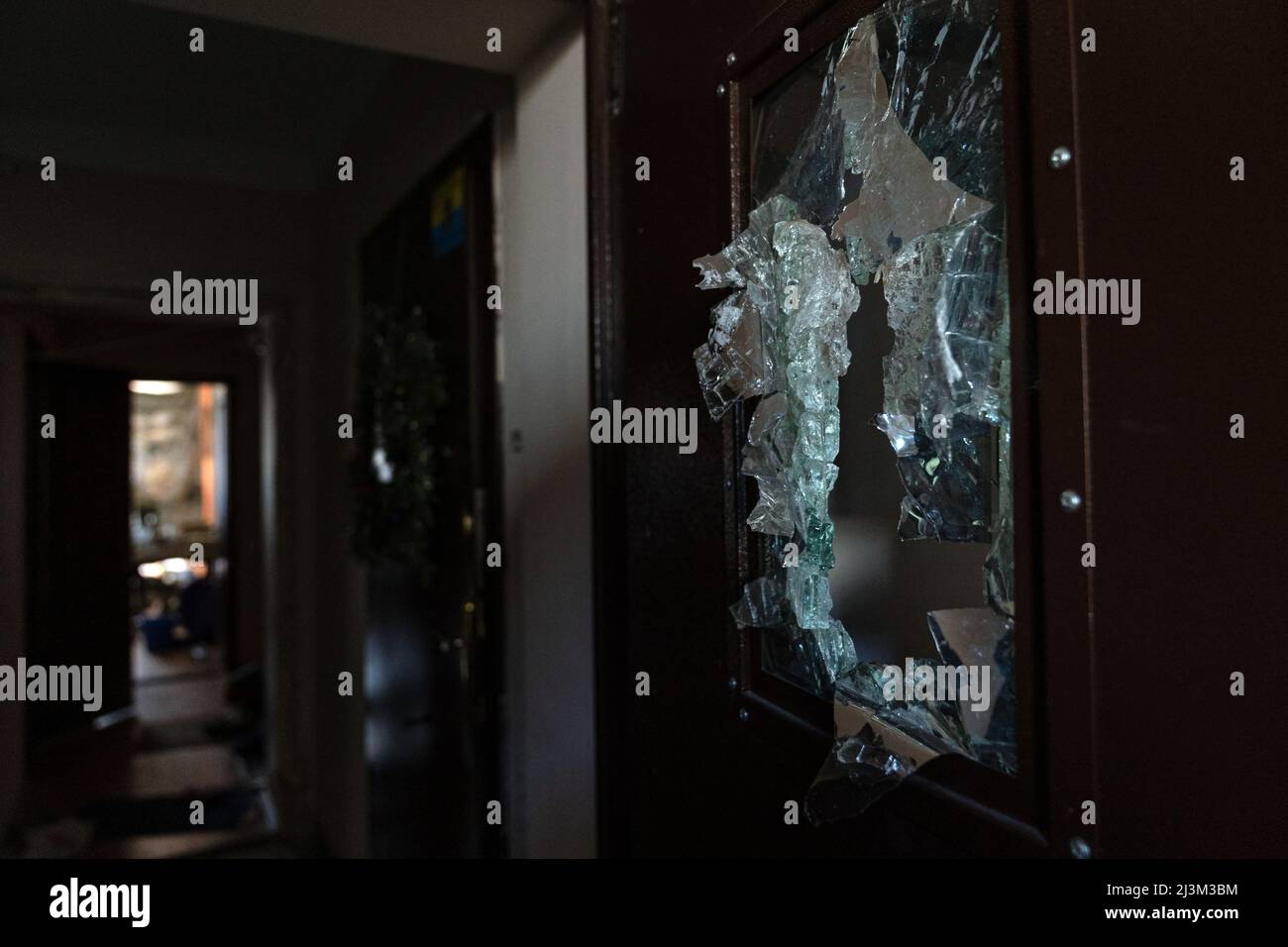 Eine gebrochene Glasscheibe in einer Tür ist in einem Wohngebäude nach der Befreiung der Stadt von russischen Eindringlingen abgebildet, Bucha, Region Kiew, Nordukraine, April 7, 2022. Nach Angaben des Bürgermeisters wurden nach einem Massenmord in Bucha mehr als 300 Einwohner der Stadt tot aufgefunden. Die Ukraine hat den Internationalen Strafgerichtshof gebeten, im Rahmen der laufenden Untersuchung der Invasion zu untersuchen, was in der Stadt geschehen ist, um festzustellen, ob eine Reihe russischer Kriegsverbrechen begangen wurden.[die russischen Behörden haben die Verantwortung verweigert und behauptet, die Ukraine habe Aufnahmen des Vorabends gefälscht Stockfoto