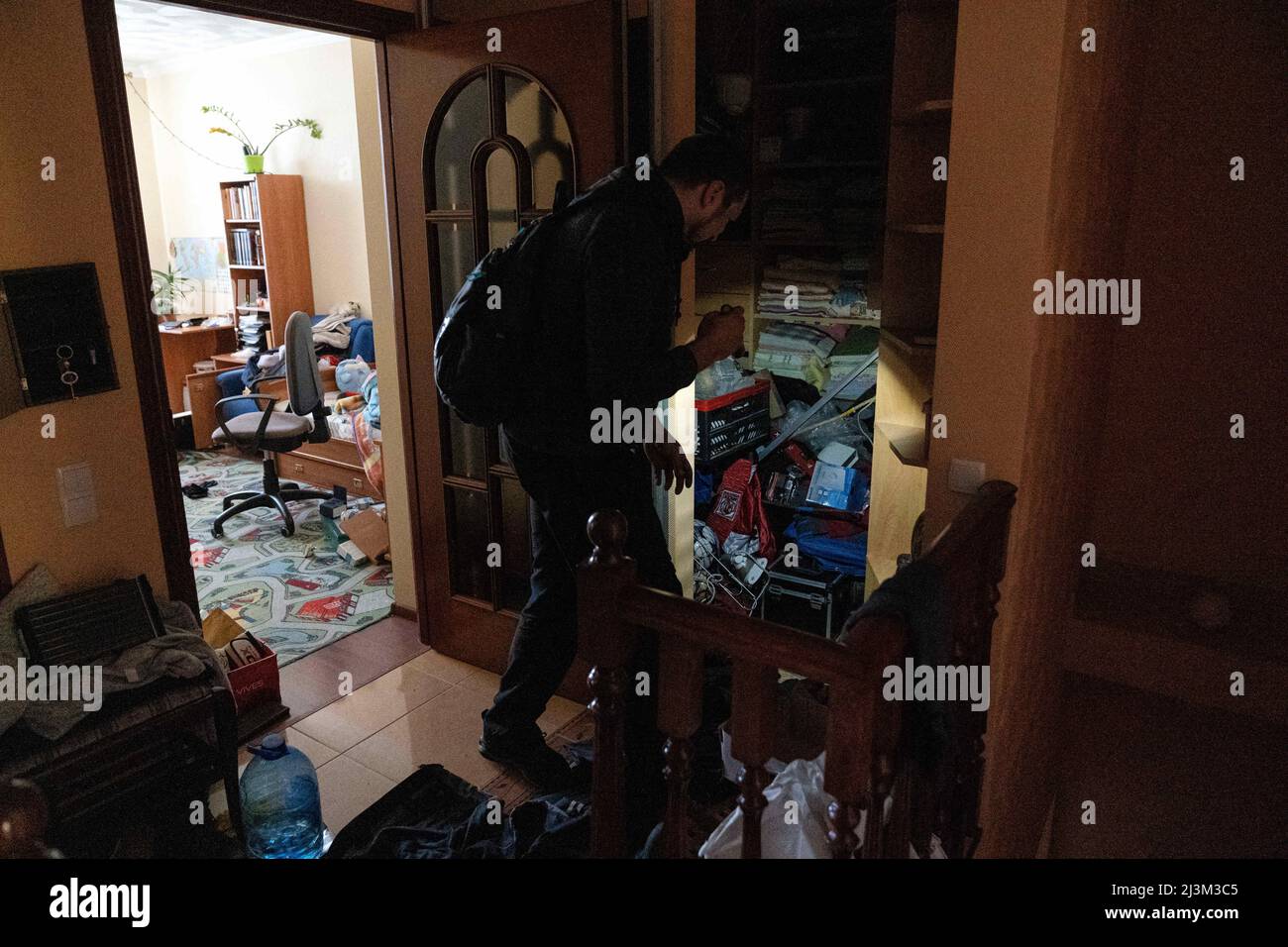 Ein Mann nutzt eine Fackel, um seine geplünderte Wohnung nach der Befreiung der Stadt von russischen Eindringlingen zu untersuchen, Bucha, Region Kiew, Nord-Ukraine, 7. April, 2022. Nach Angaben des Bürgermeisters wurden nach einem Massenmord in Bucha mehr als 300 Einwohner der Stadt tot aufgefunden. Die Ukraine hat den IStGH gebeten, zu untersuchen, was in der Stadt im Rahmen ihrer laufenden Untersuchung der Invasion geschehen ist, um festzustellen, ob eine Reihe von russischen Kriegsverbrechen begangen wurden.[die russischen Behörden haben die Verantwortung verweigert und behauptet, dass die Ukraine Aufnahmen des Ereignisses gefälscht oder inszeniert hat kill Stockfoto