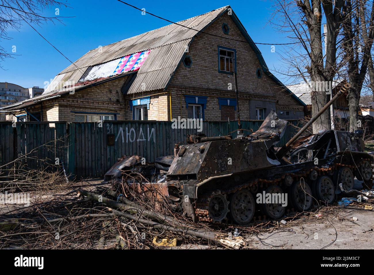 Nach der Befreiung der Stadt von den russischen Eindringlingen, Bucha, Region Kiew, Nordukraine, 7. April, ist in der Nähe eines Zauns mit dem Wort „Volk“ ein zerstörtes Militärfahrzeug zu sehen. 2022. Nach Angaben des Bürgermeisters wurden nach einem Massenmord in Bucha mehr als 300 Einwohner der Stadt tot aufgefunden. Die Ukraine hat den Internationalen Strafgerichtshof gebeten, im Rahmen der laufenden Untersuchung der Invasion zu untersuchen, was in der Stadt geschehen ist, um festzustellen, ob eine Reihe russischer Kriegsverbrechen begangen wurden.[die russischen Behörden haben die Verantwortung verweigert und behauptet, dass die Ukraine Aufnahmen von Th gefälscht habe Stockfoto