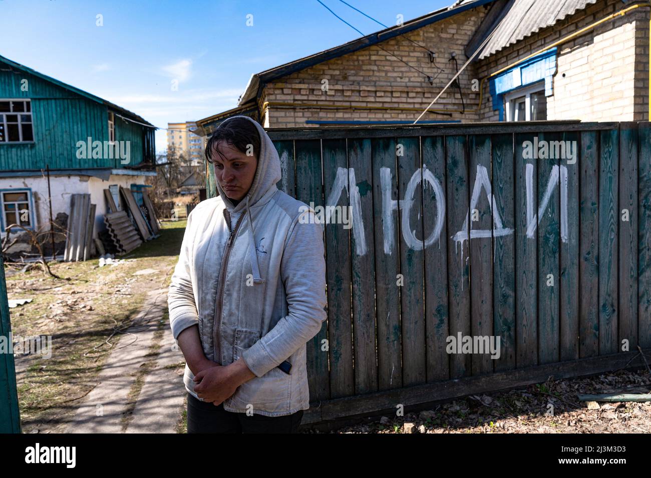 Die ortsansässige Tetiana bleibt nach der Befreiung der Stadt von den russischen Eindringlingen vor ihrem Haus, Bucha, Region Kiew, Nordukraine, April 7, 2022. Nach Angaben des Bürgermeisters wurden nach einem Massenmord in Bucha mehr als 300 Einwohner der Stadt tot aufgefunden. Die Ukraine hat den IStGH gebeten, zu untersuchen, was in der Stadt im Rahmen ihrer laufenden Untersuchung der Invasion geschehen ist, um festzustellen, ob eine Reihe von russischen Kriegsverbrechen begangen wurden.[die russischen Behörden haben die Verantwortung verweigert und behauptet, dass die Ukraine Aufnahmen des Ereignisses gefälscht oder inszeniert hat Es wird getötet Stockfoto
