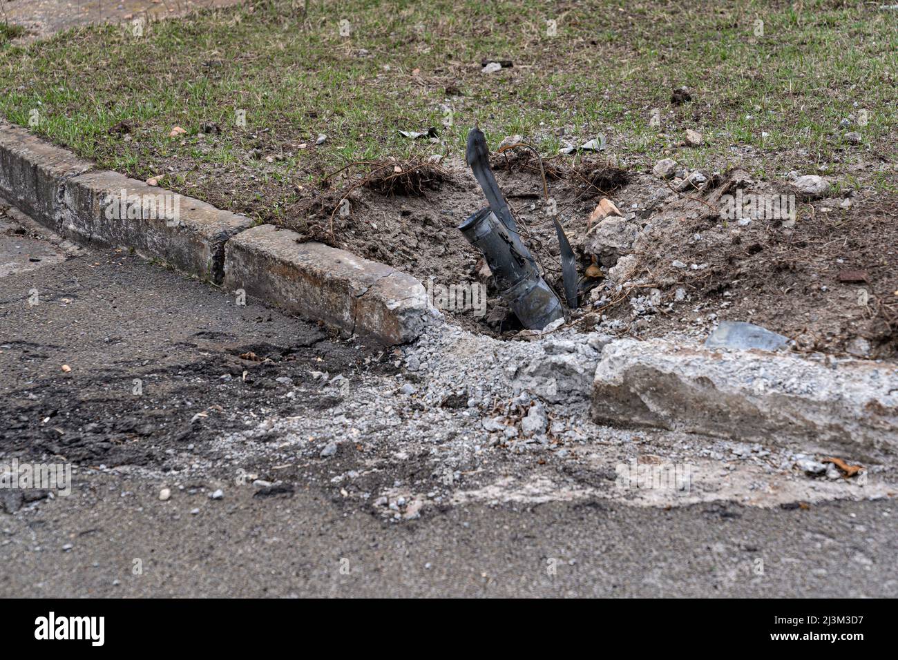 Nach der Befreiung der Stadt von den russischen Eindringlingen, Bucha, Region Kiew, Nordukraine, im April 7, ist in der Nähe einer Bordsteinkante eine Muschel im Boden festgeklemmt. 2022. Nach Angaben des Bürgermeisters wurden nach einem Massenmord in Bucha mehr als 300 Einwohner der Stadt tot aufgefunden. Die Ukraine hat den IStGH gebeten, zu untersuchen, was in der Stadt im Rahmen ihrer laufenden Untersuchung der Invasion geschehen ist, um festzustellen, ob eine Reihe von russischen Kriegsverbrechen begangen wurden.[die russischen Behörden haben die Verantwortung verweigert und behauptet, dass die Ukraine Aufnahmen des Ereignisses gefälscht oder inszeniert hat Tötungen selbst Stockfoto