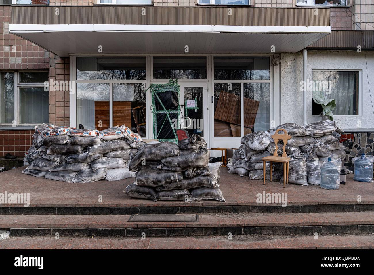 Am Eingang eines Gebäudes werden Sandsäcke gestapelt, wie man nach der Befreiung der Stadt von den russischen Eindringlingen sehen kann, Bucha, Region Kiew, Nord-Ukraine, April 7, 2022. Nach Angaben des Bürgermeisters wurden nach einem Massenmord in Bucha mehr als 300 Einwohner der Stadt tot aufgefunden. Die Ukraine hat den IStGH gebeten, zu untersuchen, was in der Stadt im Rahmen ihrer laufenden Untersuchung der Invasion geschehen ist, um festzustellen, ob eine Reihe von russischen Kriegsverbrechen begangen wurden.[die russischen Behörden haben die Verantwortung verweigert und behauptet, dass die Ukraine Aufnahmen des Ereignisses gefälscht oder inszeniert hat k Stockfoto