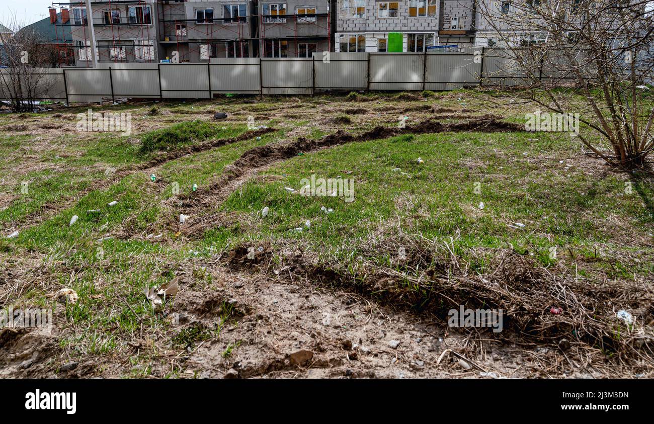 Die Spuren eines Militärfahrzeugs sind nach der Befreiung der Stadt von den russischen Eindringlingen auf dem Rasen sichtbar, Bucha, Region Kiew, Nord-Ukraine, April 7, 2022. Nach Angaben des Bürgermeisters wurden nach einem Massenmord in Bucha mehr als 300 Einwohner der Stadt tot aufgefunden. Die Ukraine hat den Internationalen Strafgerichtshof gebeten, im Rahmen der laufenden Untersuchung der Invasion zu untersuchen, was in der Stadt geschehen ist, um festzustellen, ob eine Reihe russischer Kriegsverbrechen begangen wurden.[die russischen Behörden haben die Verantwortung verweigert und behauptet, dass die Ukraine Aufnahmen des Ereignisses gefälscht oder inszeniert habe Stockfoto