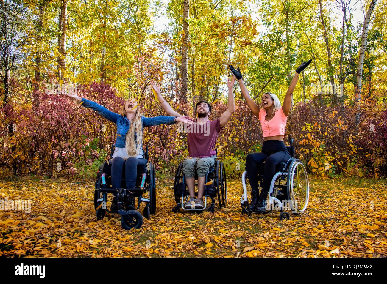 Eine Gruppe von drei jungen Querschnittsgelähmten in einem Park an einem schönen Herbsttag; Edmonton, Alberta, Kanada Stockfoto