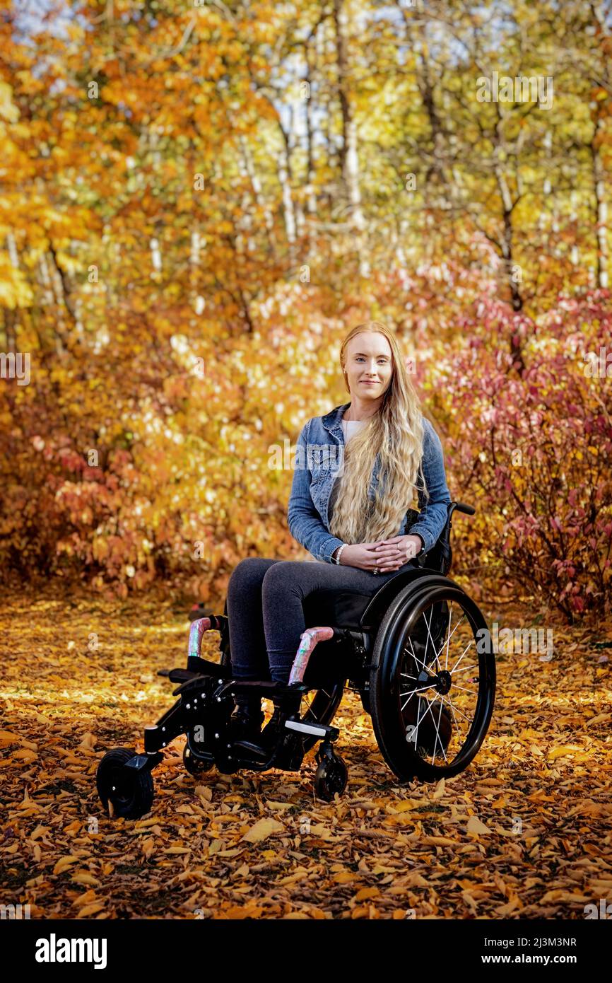 Eine junge querschnittsgelähmte Frau in ihrem Rollstuhl an einem schönen Herbsttag in einem Park; Edmonton, Alberta, Kanada Stockfoto