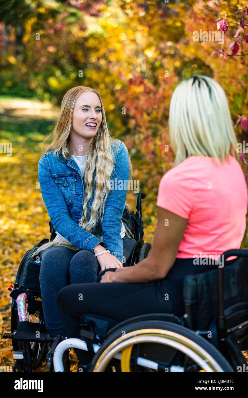 Zwei junge Frauen, die an einem schönen Herbsttag im Rollstuhl paraplegiker sind, besuchen gemeinsam einen Park; Edmonton, Alberta, Kanada Stockfoto