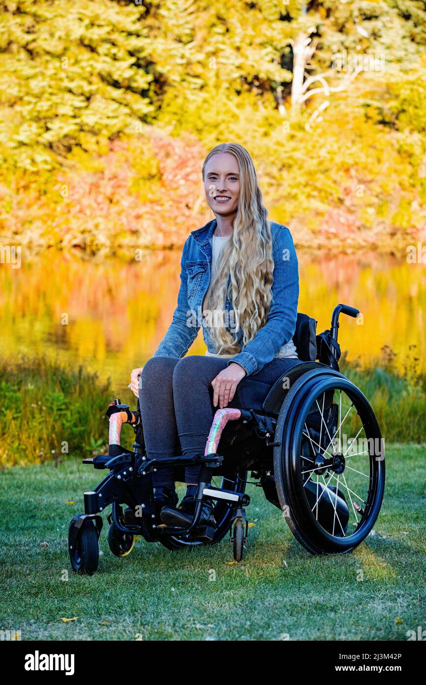 Junge querschnittsgelähmte Frau in ihrem Rollstuhl in einem Park an einem schönen Herbsttag; Edmonton, Alberta, Kanada Stockfoto