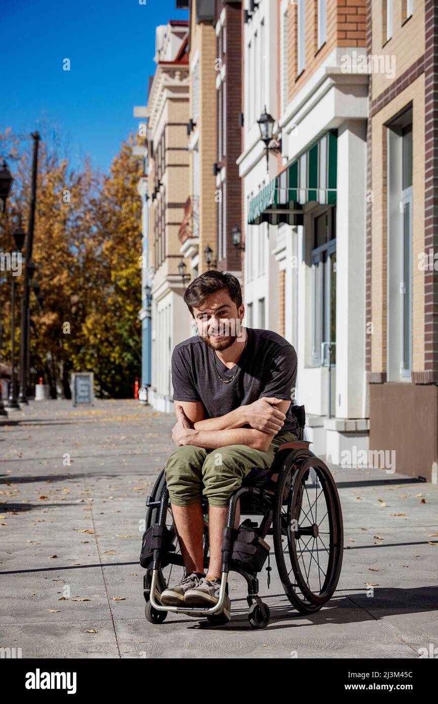 Außenportrait eines jungen querschnittsgelähmten Mannes in seinem Rollstuhl auf einem Bürgersteig an einem schönen Herbsttag; Edmonton, Alberta, Kanada Stockfoto