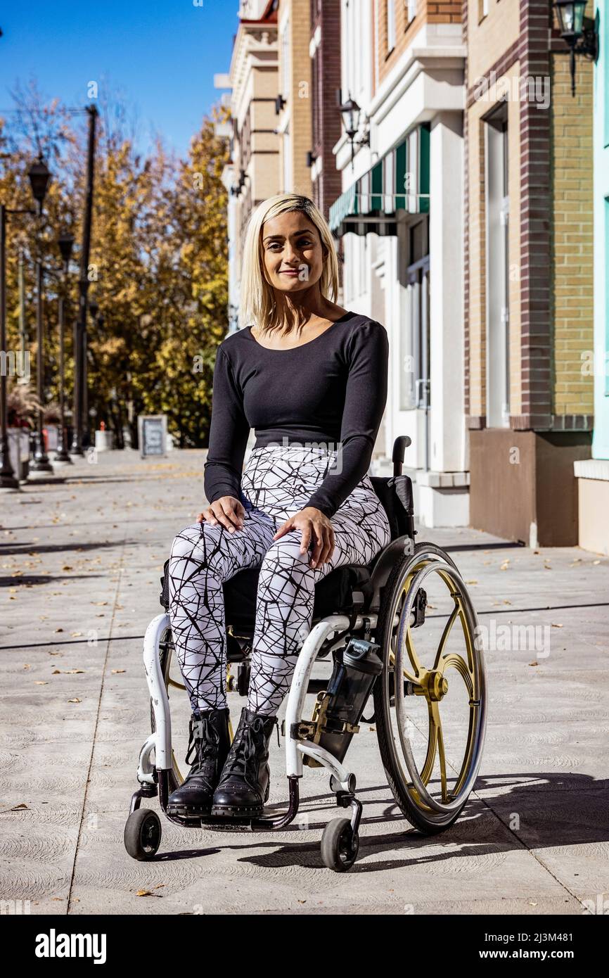 Außenportrait einer jungen querschnittsgelähmten Frau in ihrem Rollstuhl auf einem Bürgersteig an einem schönen Herbsttag; Edmonton, Alberta, Kanada Stockfoto
