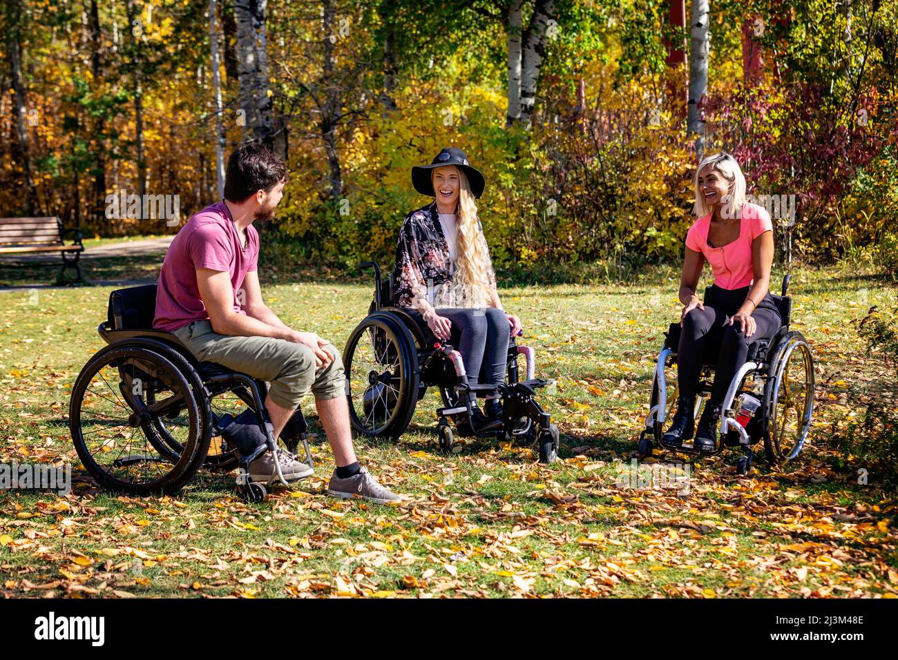 Eine Gruppe von drei jungen Querschnittsgelähmten, die an einem schönen Herbsttag gemeinsam in einem Park in Edmonton, Alberta, Kanada, unterwegs waren Stockfoto