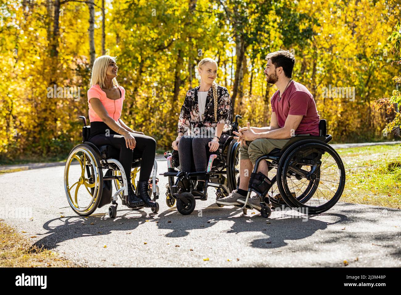 Eine Gruppe von drei jungen Querschnittsgelähmten, die an einem schönen Herbsttag gemeinsam in einem Park in Edmonton, Alberta, Kanada, unterwegs waren Stockfoto