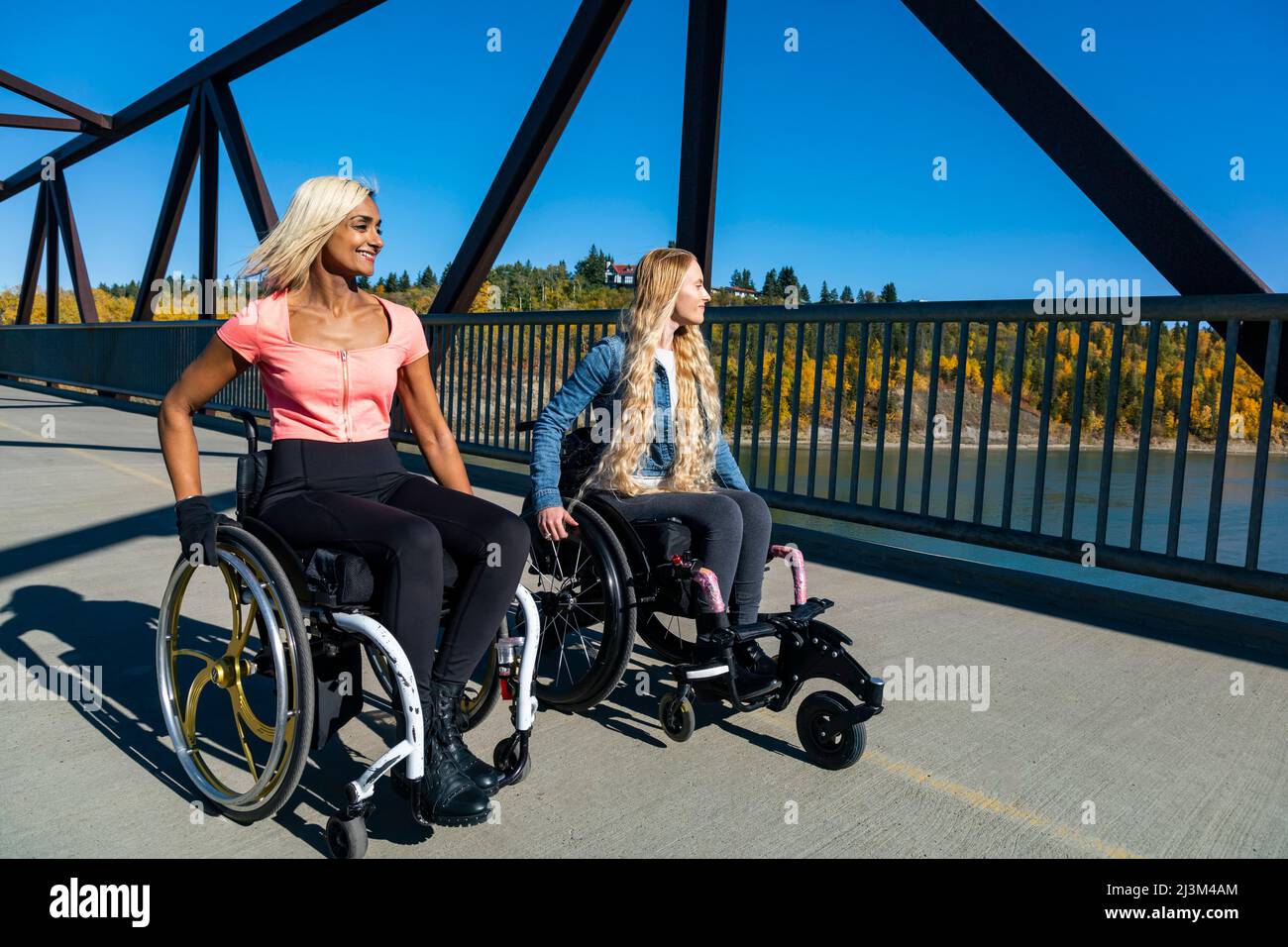 Zwei junge querschnittsgelähmte Frauen in ihren Rollstühlen, die an einem schönen Herbsttag in einem Park sitzen; Edmonton, Alberta, Kanada Stockfoto