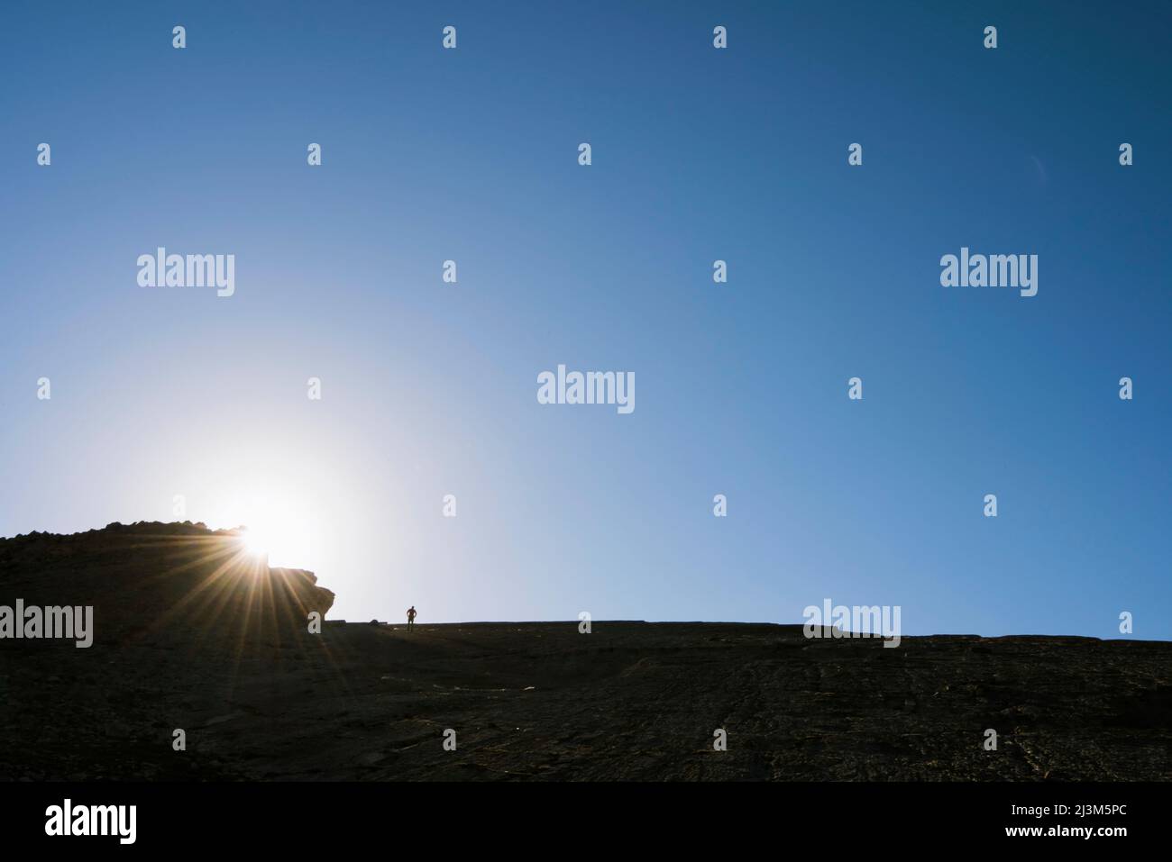 Ein Expeditionsmitglied kehrt während der Wanderung in Richtung Dark Star, einem Kalksteinhöhlensystem im usbekischen Boysuntov-Bergmassiv, zum Camp am Rand einer Klippe zurück. Stockfoto