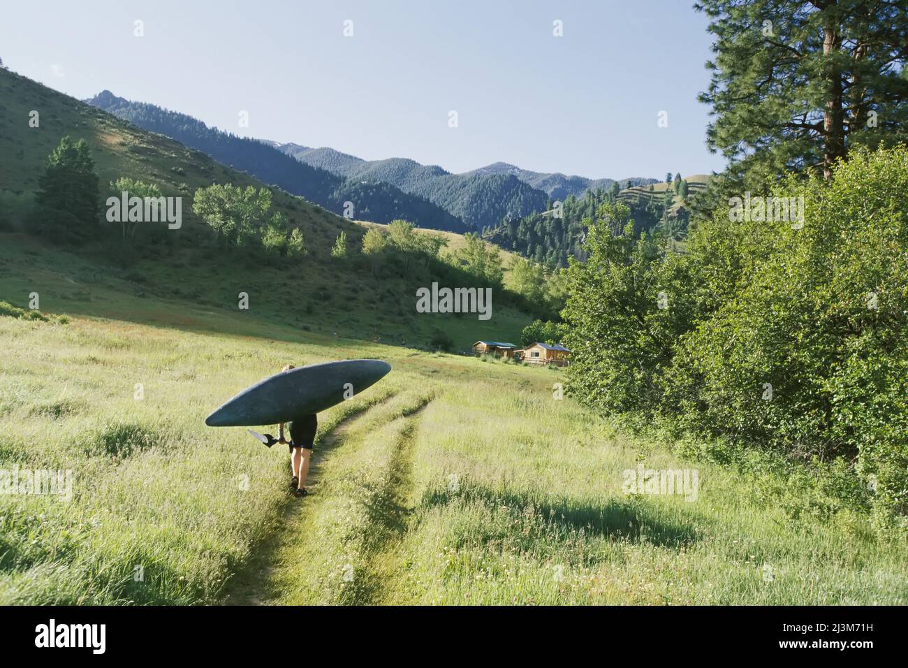 Eine Frau trägt ein Kajak in der Nähe der Mittelgabel des Salmon River.; Salmon River, Idaho. Stockfoto