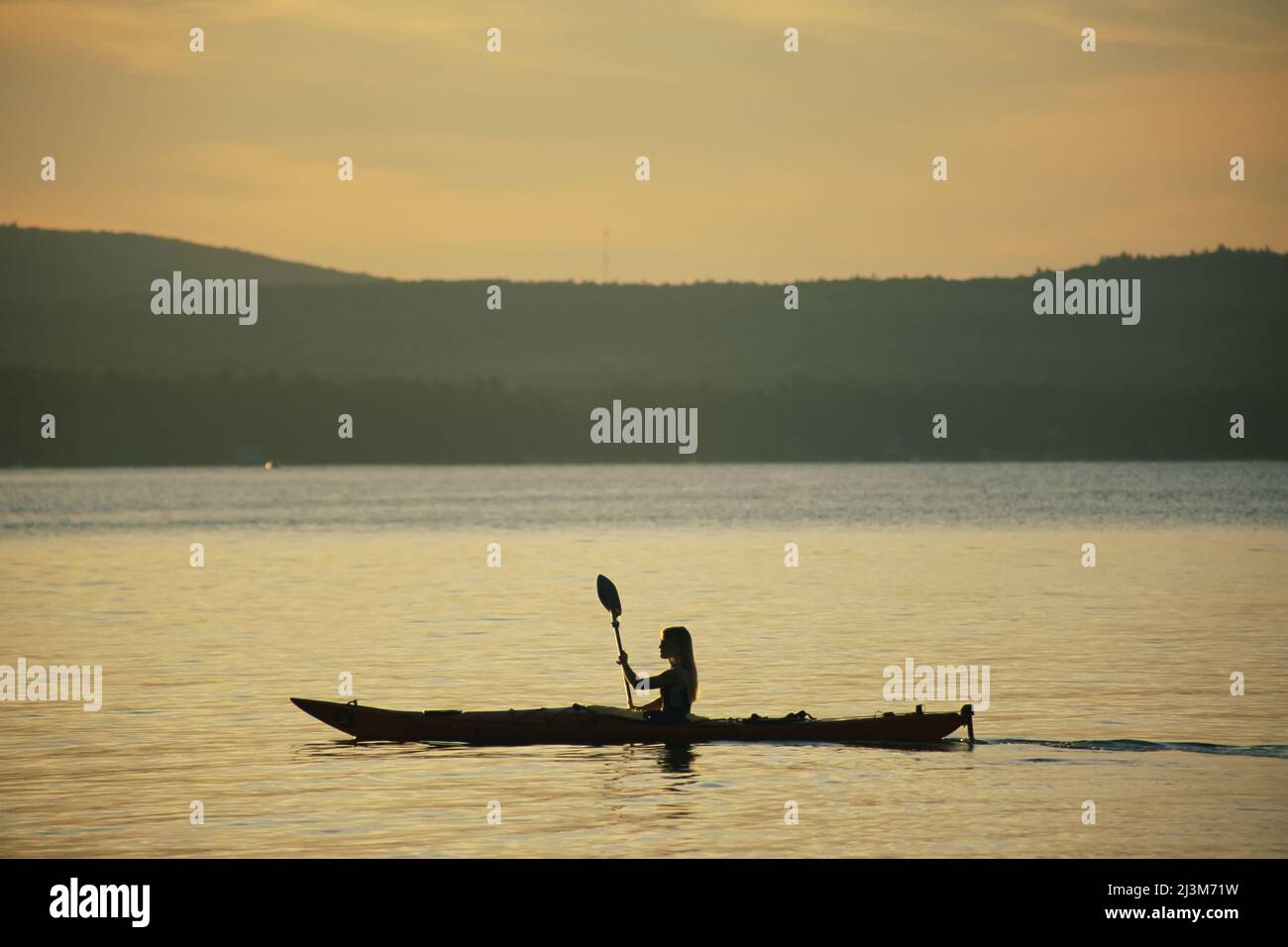 Eine Frau, die auf Sebago Lake mit dem Kajak unterwegs ist; Sebago Lake, Maine. Stockfoto