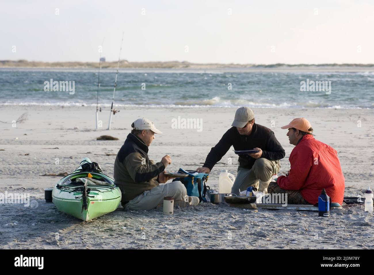 Fischer kochen Abendessen am Strand neben Kajak und Angelruten; Core Banks, North Carolina Stockfoto
