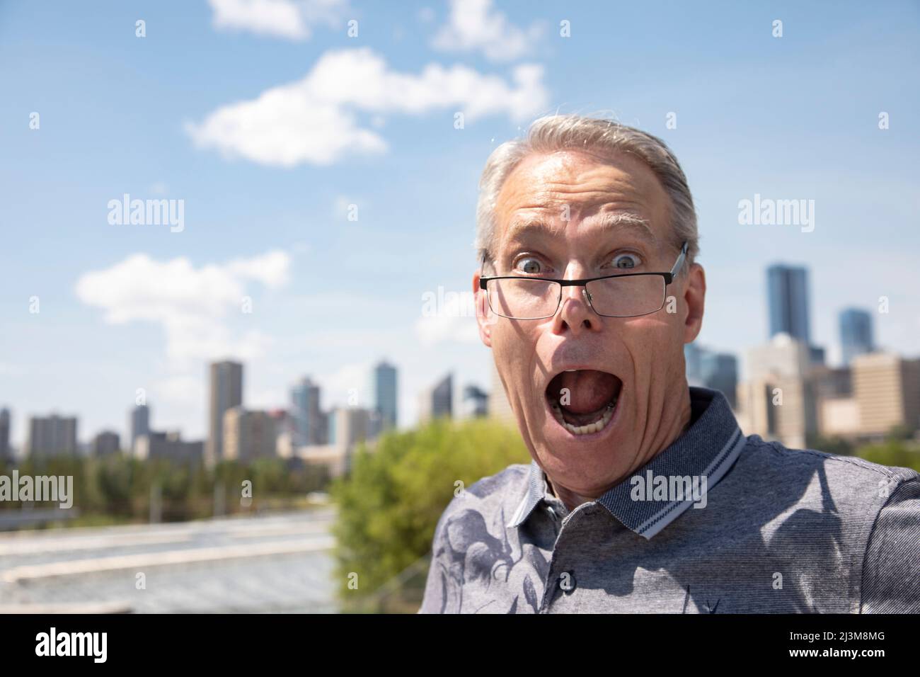 Ein älterer Mann, der im Freien steht und mit einem überraschenden Gesichtsausdruck über die Brille auf die Kamera blickt; Edmonton, Alberta, Kanada Stockfoto