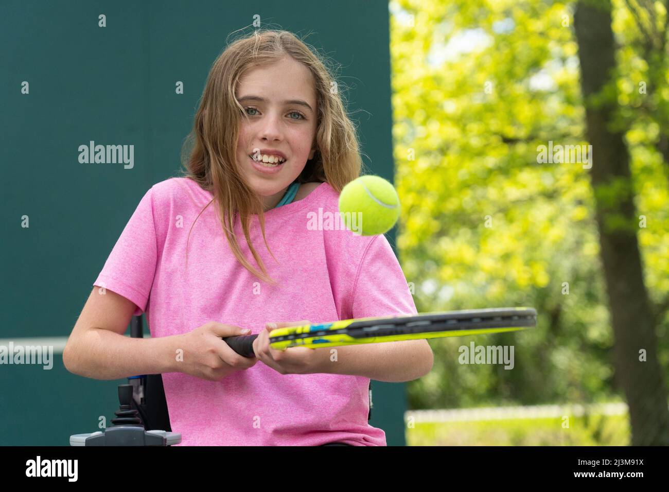 Mädchen mit Ullrich Congenital Muscular Dystrophy spielt Tennis in ihrem Rollstuhl; Cabin John, Maryland, Vereinigte Staaten von Amerika Stockfoto