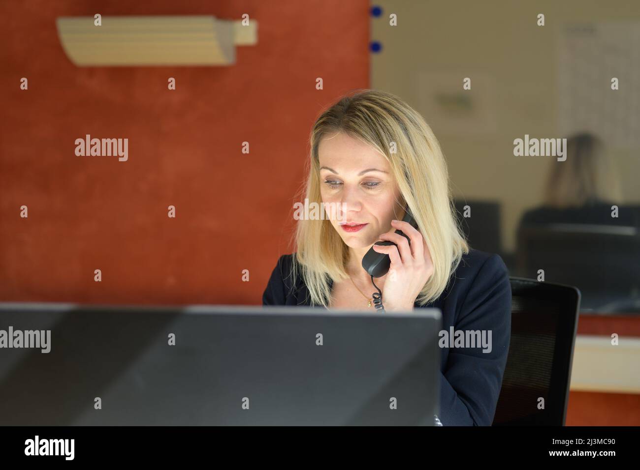 Porträt einer Geschäftsfrau in formeller Kleidung, die am Desktop-Computer arbeitet, während sie im Büro über ein Festnetztelefon sprach Stockfoto