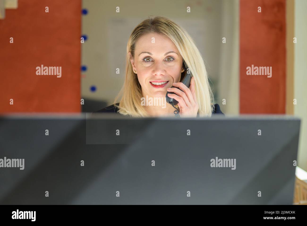 Porträt einer Geschäftsfrau in formeller Kleidung, die am Desktop-Computer arbeitet, während sie im Büro über ein Festnetztelefon sprach Stockfoto