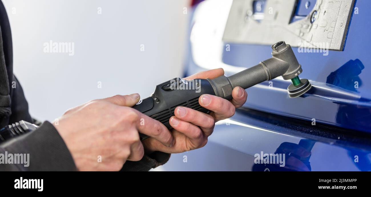 Car Details - Mann mit Orbitalpolierer in einem Auto Polieren Reparaturwerkstatt, Auto Detaillierung Konzept, Industrie Stockfoto