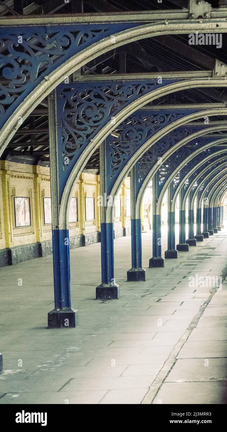 Ein alter Eisenbahnzug aus Gussmetall (debarcadere) über dem Bahnlandeplatz am Bahnhof. Gleichmäßig verteilte Spalten und ein Beispiel für eine lineare Sicht Stockfoto