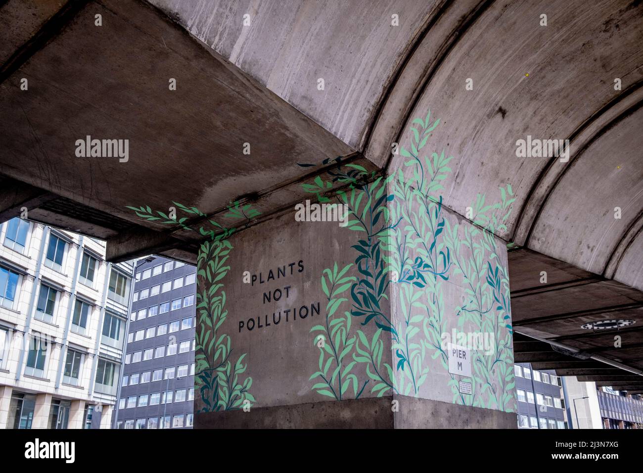 Unter der Betonstruktur wurde am 6.. April 2022 in London, England, auf einer Säule der Hammersmith-Überführung Kunstwerke geschrieben, die „Pflanzen und keine Verschmutzung“ proklamieren. Stockfoto