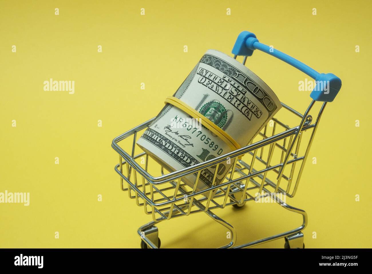 In einen Schlauch gerollte Dollars liegen in einem Einkaufskorb. Stockfoto