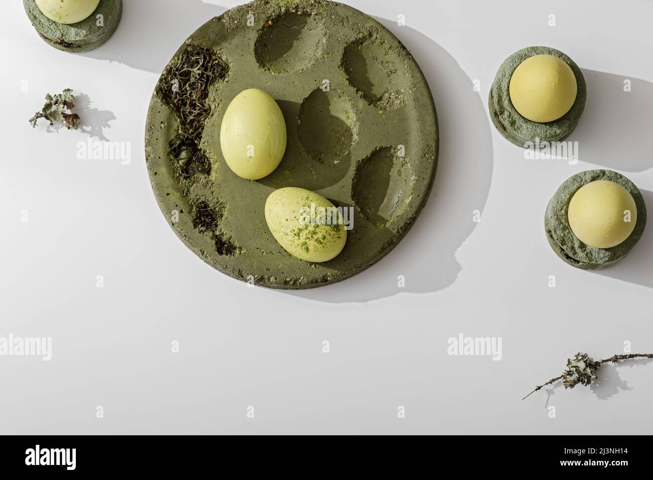 Zero Waste Osterkonzept. Ostereier mit Matcha-Tee in moosgrünem Zementtablett gefärbt. Umweltfreundlicher Lebensstil. Moderne und zeitgenössische Inneneinrichtung de Stockfoto