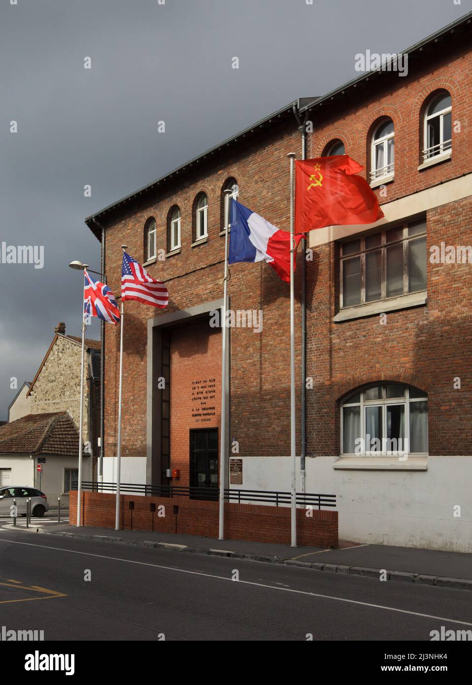 Die Nationalflaggen des Vereinigten Königreichs, der Vereinigten Staaten von Amerika, Frankreichs und der Sowjetunion schwingen sich am Eingang des Museums der Kapitulation (Musée de la Redadition) in Reims, Frankreich. Das erste deutsche Kapitulationsinstrument, das den Zweiten Weltkrieg in Europa beendete, wurde in diesem Gebäude am 7. Mai 1945 um 02:41 Uhr mitteleuropäischer Zeit (MEZ) unterzeichnet. Stockfoto