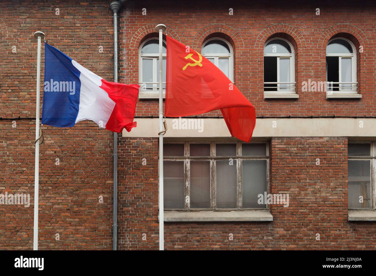 Am Eingang des Museums der Kapitulation (Musée de la Redadition) in Reims, Frankreich, winken die Nationalflaggen Frankreichs und der Sowjetunion. Das erste deutsche Kapitulationsinstrument, das den Zweiten Weltkrieg in Europa beendete, wurde in diesem Gebäude am 7. Mai 1945 um 02:41 Uhr mitteleuropäischer Zeit (MEZ) unterzeichnet. Stockfoto