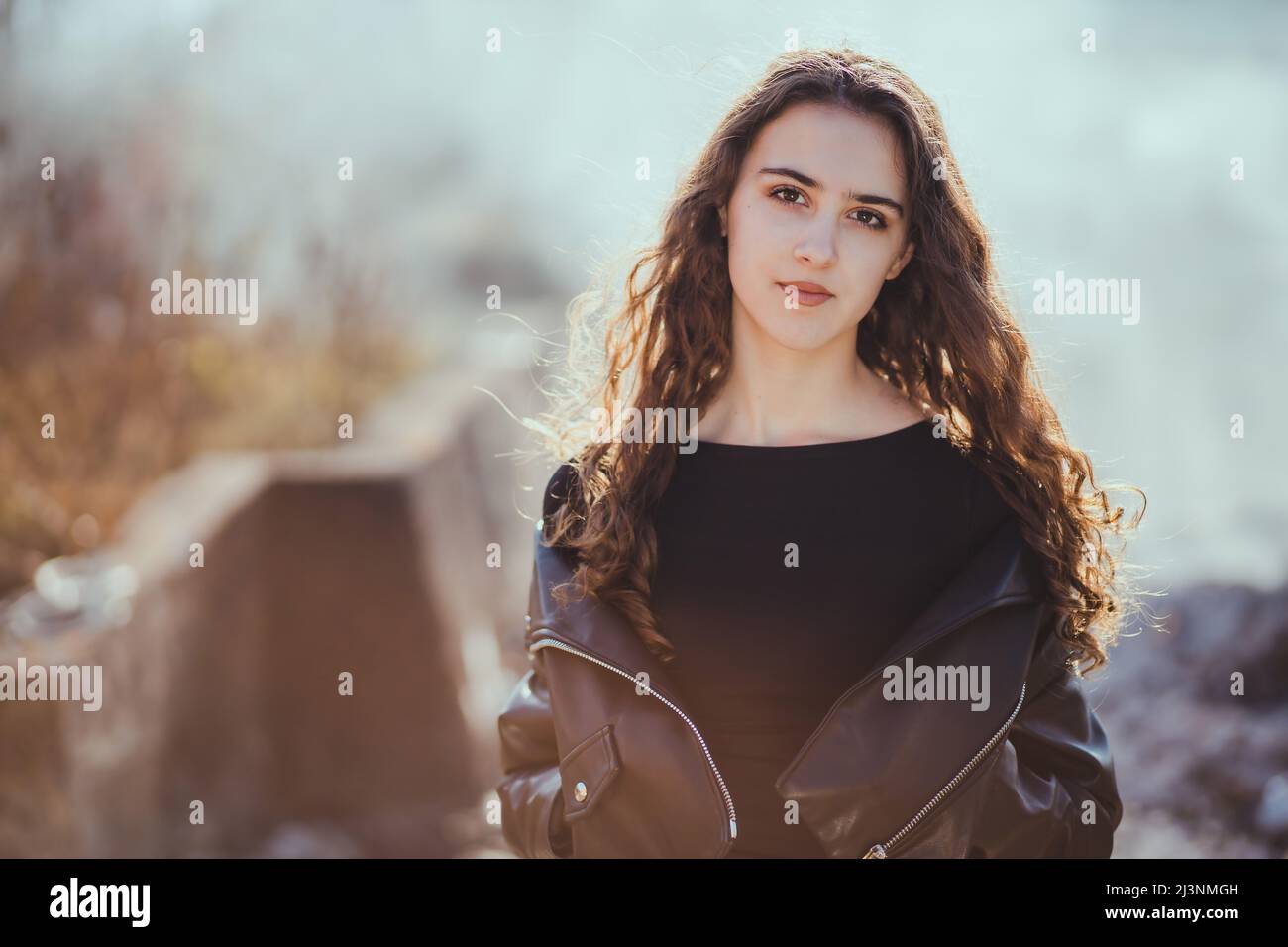 Outdoor-Porträt eines schönen Teenager Brünette Mädchen in der schwarzen Lederjacke mit Rauch im Hintergrund Stockfoto