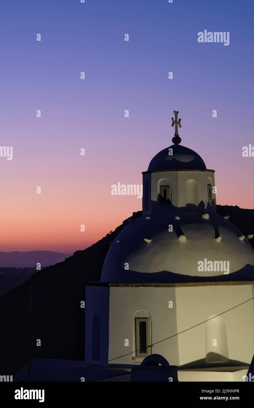 Blick auf eine traditionelle griechische Kirche in Santorini und einen atemberaubenden violetten Sonnenuntergang Stockfoto