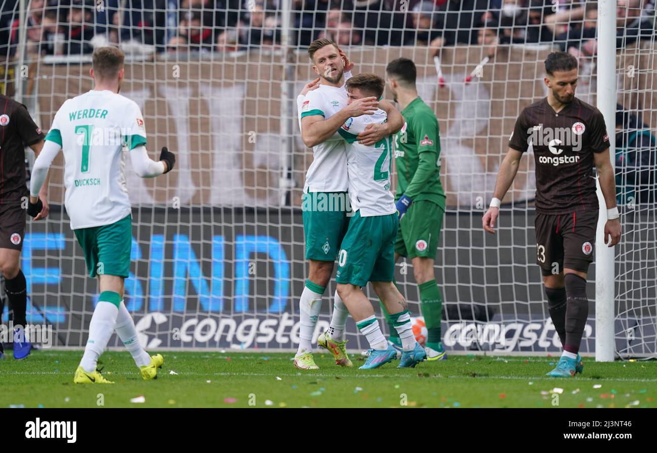 09. April 2022, Hamburg: Fußball: 2. Bundesliga, Matchday 29, FC St. Pauli - Werder Bremen, im Millerntor-Stadion. Bremens Torschütze Niclas Füllkrug (2. v.l.) feiert mit dem Bremer Marvin Ducksch (l.) und Romano Schmid nach seinem Tor 1:1. St. Paulis Leart Paqarada befindet sich rechts im Bild. Foto: Marcus Brandt/dpa - WICHTIGER HINWEIS: Gemäß den Anforderungen der DFL Deutsche Fußball Liga und des DFB Deutscher Fußball-Bund ist es untersagt, im Stadion und/oder vom Spiel aufgenommene Fotos in Form von Sequenzbildern und/oder Vid zu verwenden oder zu verwenden Stockfoto