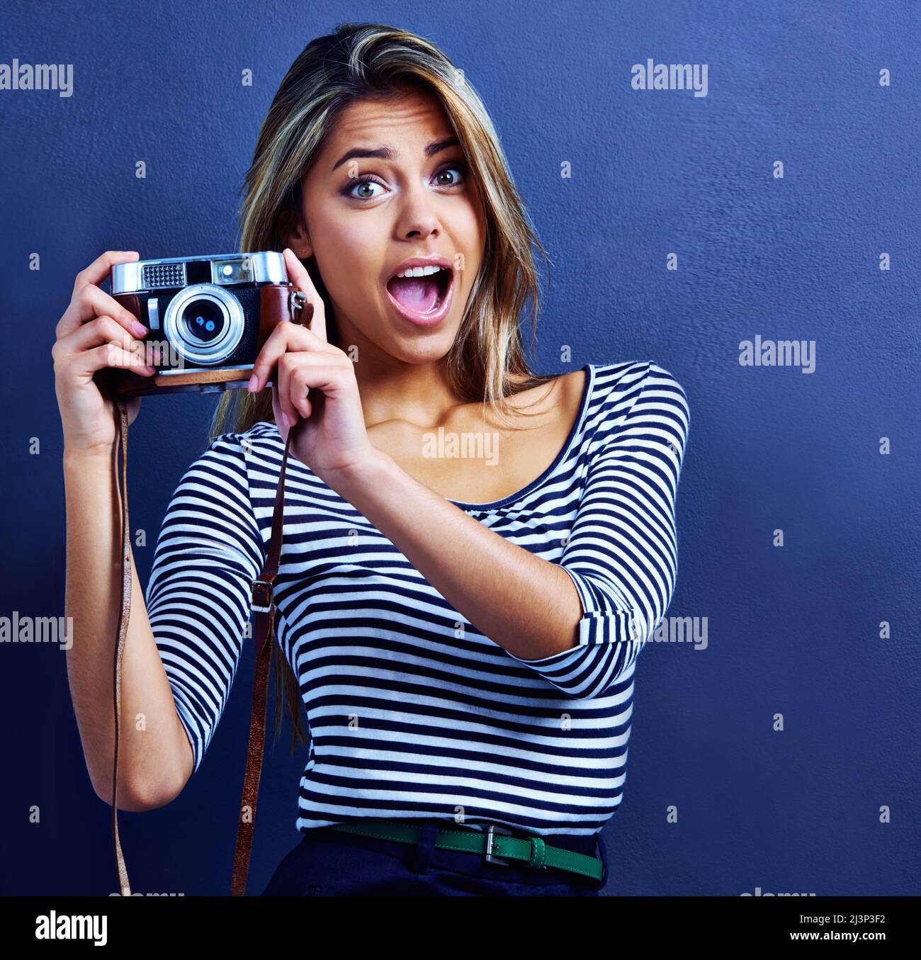 Halte die Pose. Aufnahme einer überraschten jungen Frau mit einer Kamera. Stockfoto