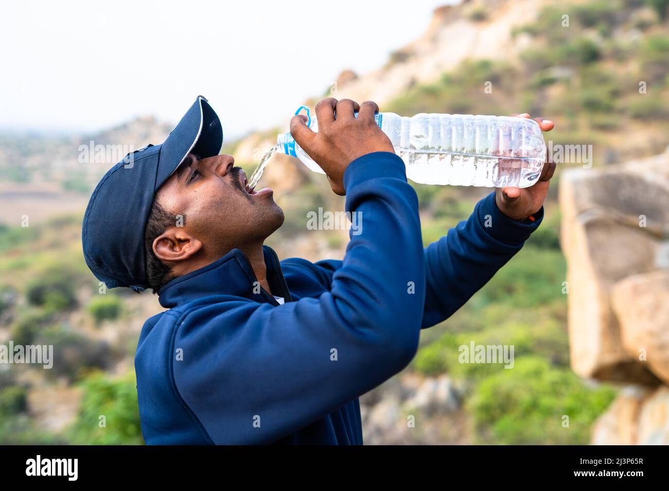 Durstiger Wanderer, der im Sommer auf dem Hügel trinkt - Konzept der Entspannungswärmewelle und gesunder Lebensstil Stockfoto