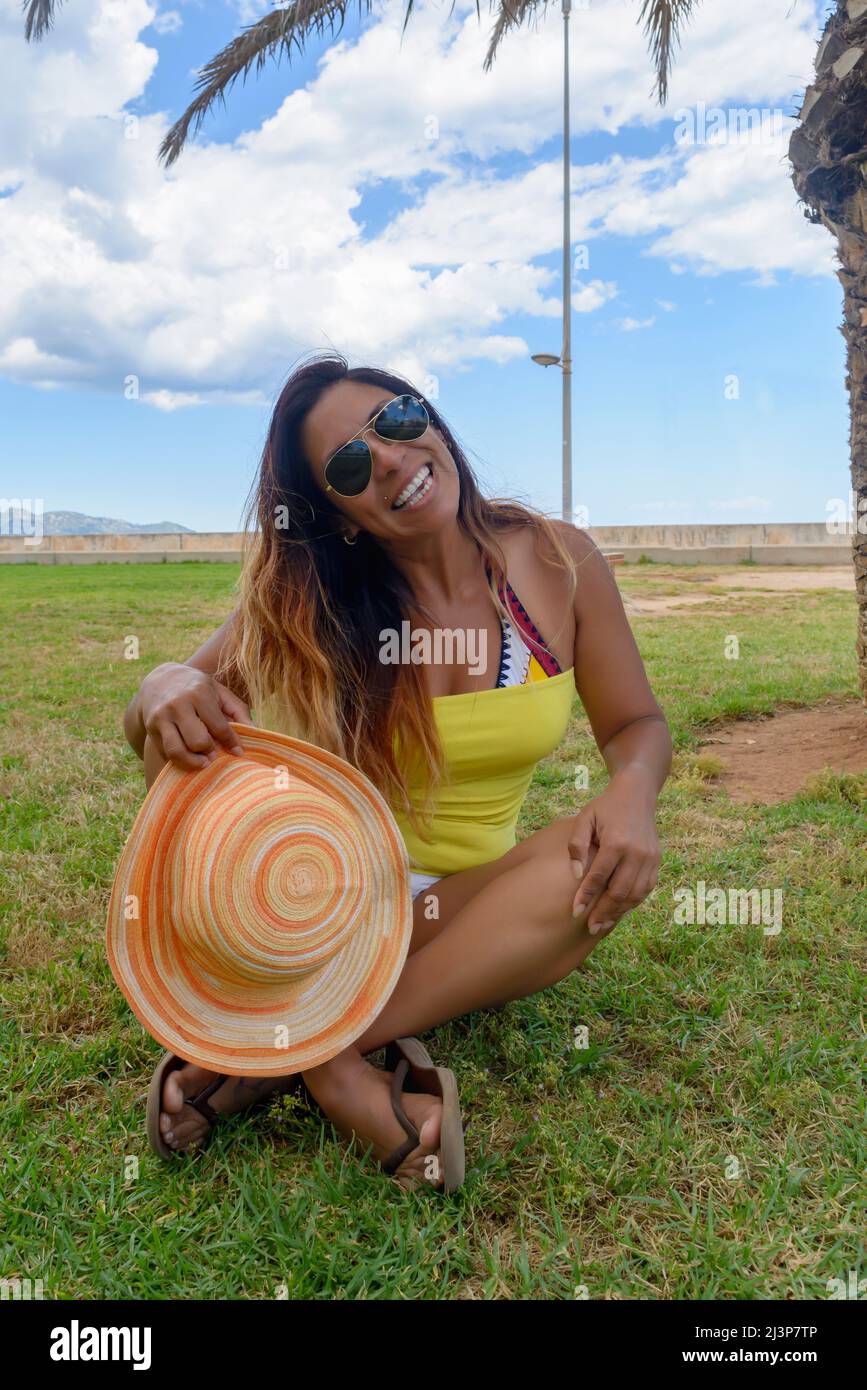 Glückliche Frau mittleren Alters lächelt in ihrem Urlaub auf mallorca, mit Hut Sonnenbrille und Bikini, Reisekonzept Stockfoto