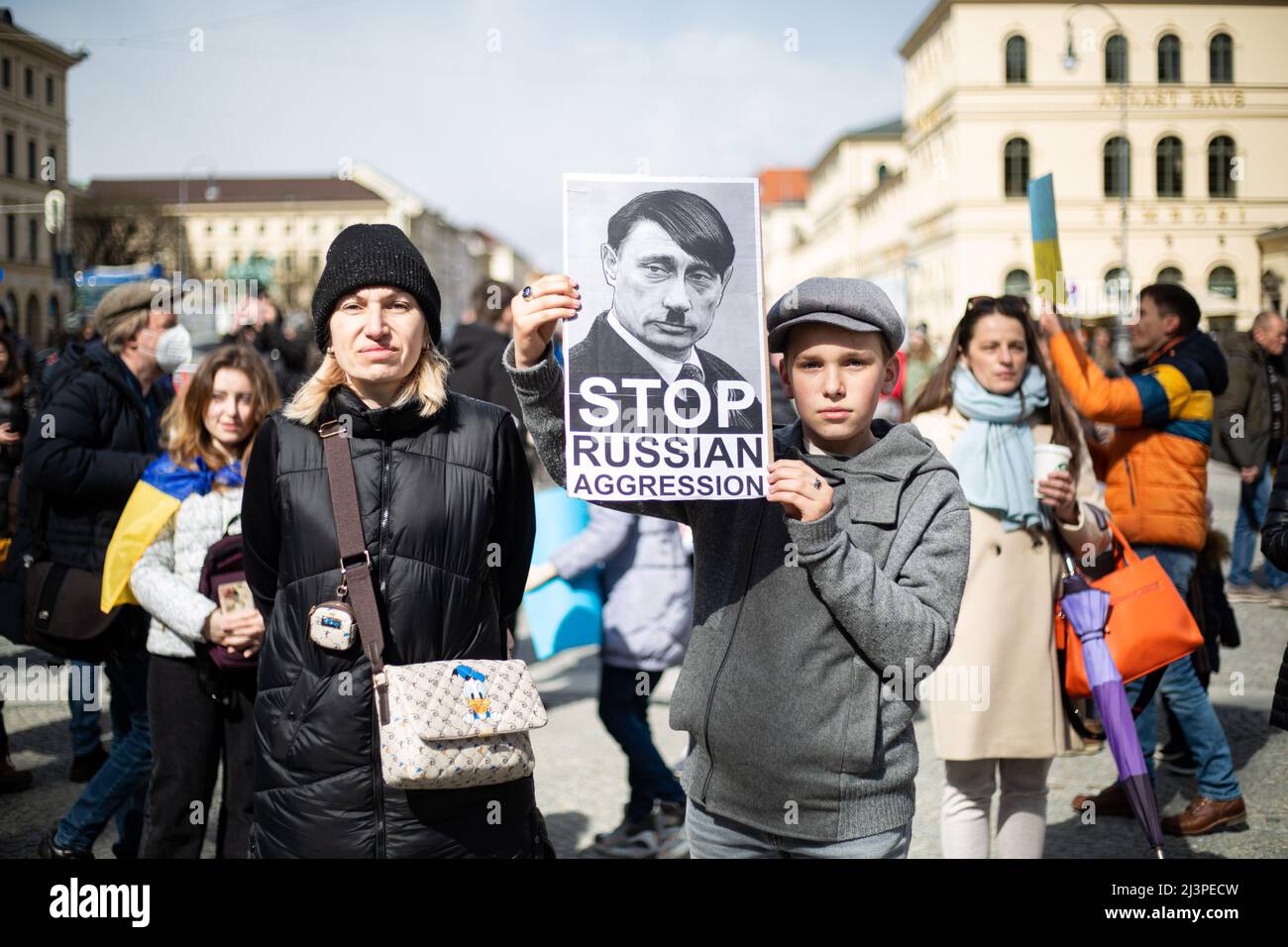 München, Deutschland. 09. April 2022. Junge mit Schild, das Putin zeigt, als Hitler liest: „ Stoppt die Aggression Russlands“. Am 9. April versammelten sich 2022 Menschen in München, Deutschland, um gegen die russische Invasion in der Ukraine zu protestieren und sich an die Toten des Massakers von Bucha zu erinnern. (Foto: Alexander Pohl/Sipa USA) Quelle: SIPA USA/Alamy Live News Stockfoto