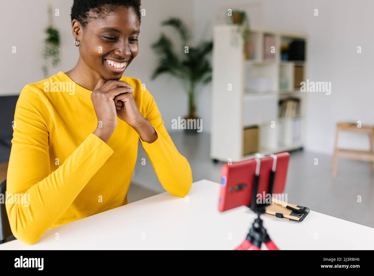 Glückliche junge afrikanische Frau, die mit dem Smartphone Videos überträgt und aufnimmt Stockfoto