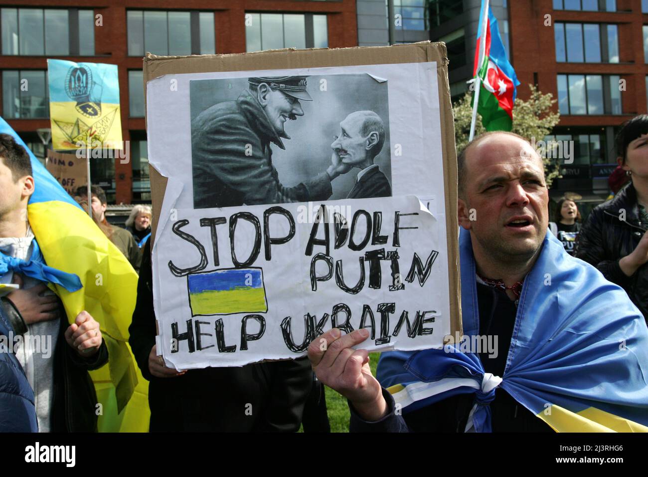 Ein Mitglied der ukrainischen Gemeinde von Manchester hält ein Plakat während der Reden, die bei einem lautstarken Protest im Stadtzentrum gehalten werden. Das Plakat zeigt den russischen Präsidenten Wladimir Putin als einen weiteren „Adolf Hitler“ und bittet um „Hilfe für die Ukraine“ rund 200 Mitglieder der ukrainischen Gemeinde in Manchester sowie Ukrainer des Kulturzentrums „Dnipro“ marschierten durch das Stadtzentrum. Sie forderten ein Ende der Feindseligkeiten, der Invasion und des Mordes an Zivilisten, die gegen sie verübt wurden, seit Russland im Februar dieses Jahres ohne Provokation in die Ukraine einmarschierte. Viele ukrainische Kinder waren pre Stockfoto